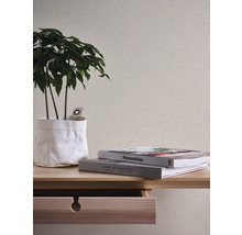 Dekoratives Interieur mit gemusterter Tapete, Pflanze und Büchern auf einem Holztisch