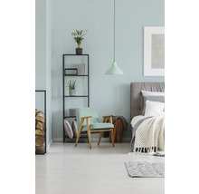 Schlafzimmer mit Bett, Sessel, Regal und Lampe