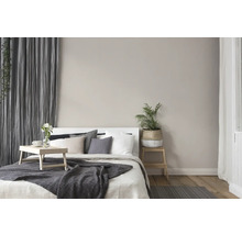 Helles Schlafzimmer mit Bett, Kissen, Decke, Vorhängen und Zimmerpflanzen