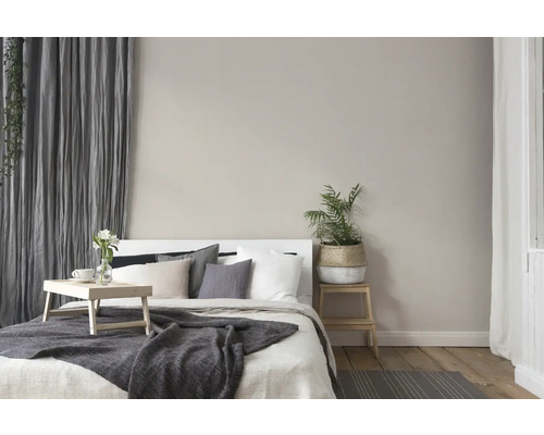 Helles Schlafzimmer mit Bett, Kissen, Decke, Vorhängen und Zimmerpflanzen