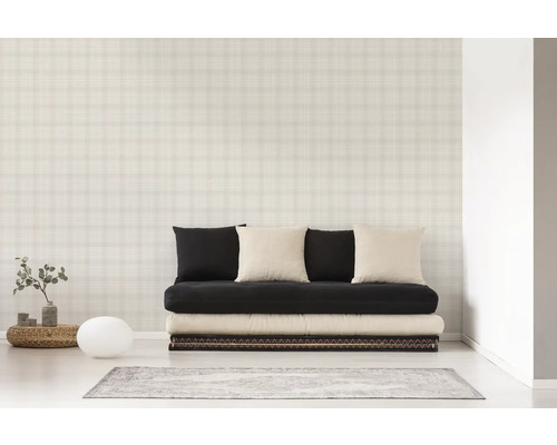 Une pièce avec un canapé, des coussins et un papier peint à carreaux.