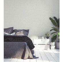 Helles Schlafzimmer mit Bett, Nachttisch und Zimmerpflanzen