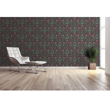 Wohnraum mit floral gemusterter Tapete, Sessel und Zimmerpflanze.