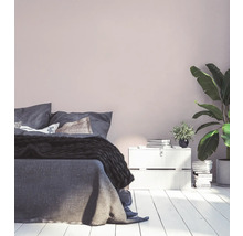 Helles Schlafzimmer mit Bett, Nachttisch und Zimmerpflanzen