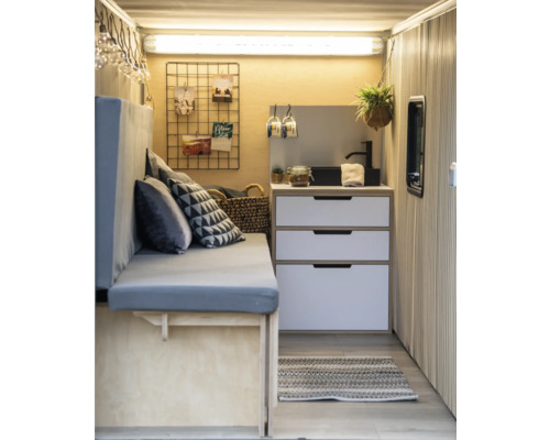 Hell gestalteter Innenraum mit Sitzbank, Schubladenkommode und dekorativen Elementen