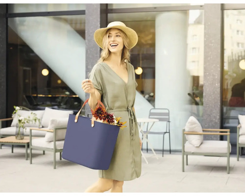 Frau mit Strohhut und blauer Tragetasche im Aussenbereich