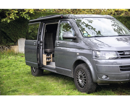 Grauer Van mit geöffneter Schiebetür und Schuhregal im Innenraum.