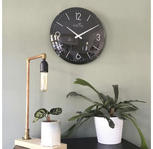 Dekorative Szene mit einer schwarzen Wanduhr, einer Tischlampe aus Kupfer und zwei Zimmerpflanzen in Töpfen.