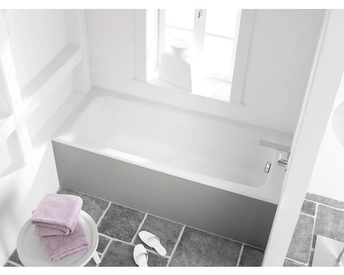 Salle de bain avec baignoire, serviettes et chaussons sur carrelage gris