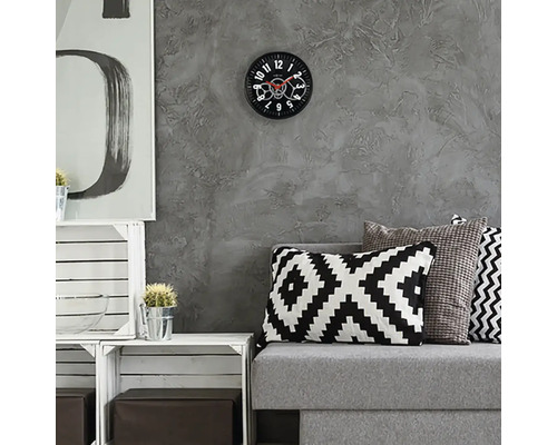 Wohnzimmer mit grauer Couch, Kissen und Wanduhr mit sichtbarem Uhrwerk