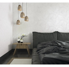 Schlafzimmer mit Bett, Nachttisch, Lampe und gemusterter Tapete