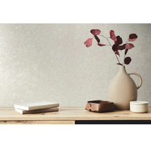 Éléments décoratifs tels qu''un vase, des livres et des bols sur une table devant un mur texturé.