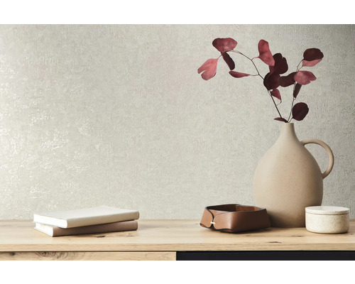 Éléments décoratifs tels qu''un vase, des livres et des bols sur une table devant un mur texturé.