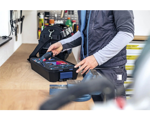 Person nimmt Akku-Bohrschrauber aus Werkzeugkoffer