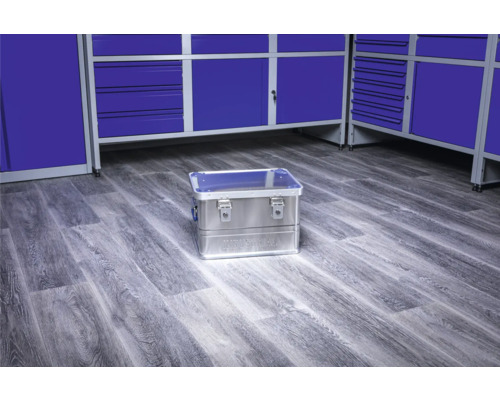 Boîte à outils en aluminium sur le sol devant des armoires d''atelier bleues