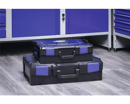 Zwei Werkzeugkoffer aus Kunststoff, gestapelt vor einer Werkbank