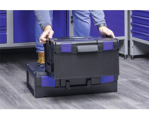 Une personne empile une boîte à outils sur une autre.