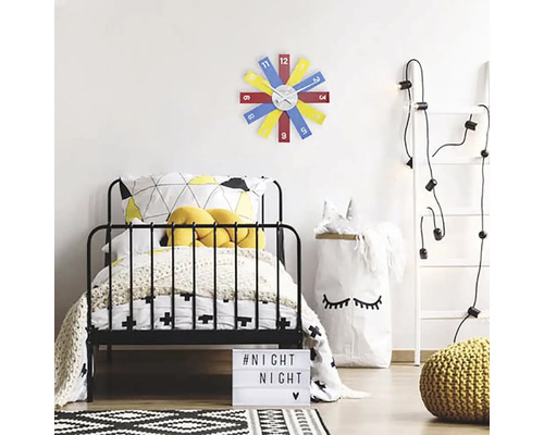 Ein Kinderzimmer mit einem Bett, einer Leiter mit Lichtern und einer farbenfrohen Wanduhr