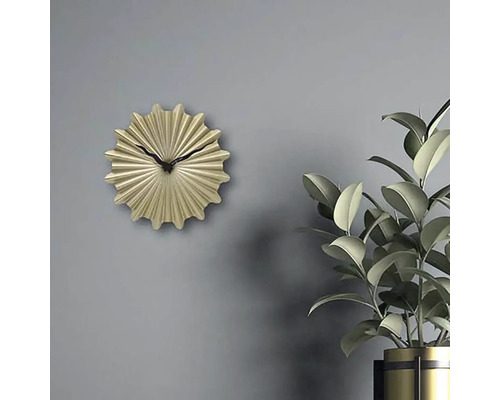 Dekorative goldfarbene Wanduhr mit schwarzem Zeiger neben Zimmerpflanze