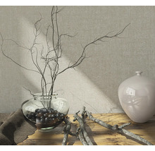 Arrangement décoratif avec vase en verre, branches et boules décoratives sur une table en bois.