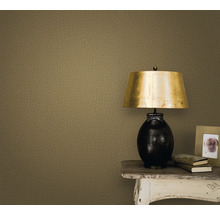 Nahaufnahme einer Wand mit einer Textiltapete, einem Nachttisch, einer Lampe, einem Bilderrahmen und Büchern.