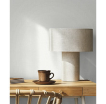 Pièce décorative avec lampe de table, tasse, carnets et chaise en rotin