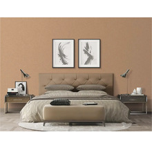 Schlafzimmer mit Doppelbett, Nachttischen und Dekoration vor einer gemusterten Tapete.