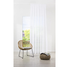 Pièce lumineuse avec rideau blanc, fauteuil en rotin et pouf avec magazine