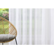 Pièce lumineuse avec rideau blanc et fauteuil en rotin