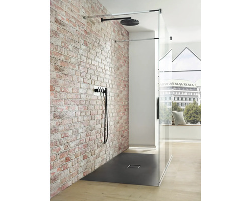 Douche à l''italienne avec douche de tête, robinetterie et receveur devant un mur de briques