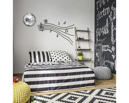 Schlafzimmer mit Bettwäsche mit Streifenmuster, Wandtattoo mit Noten und Wanduhr mit Spiegelkugeln