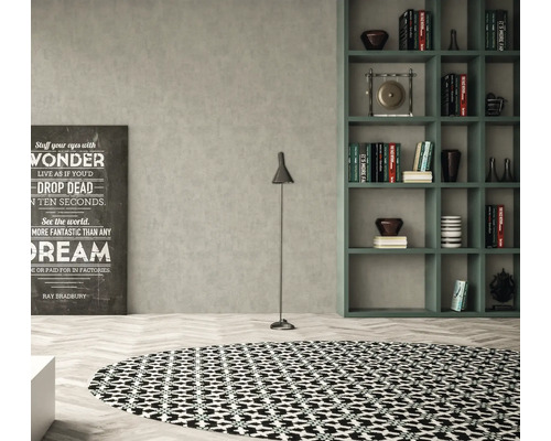 Wohnzimmer mit rundem Teppich, Stehlampe, Regal und dekorativem Schriftbild