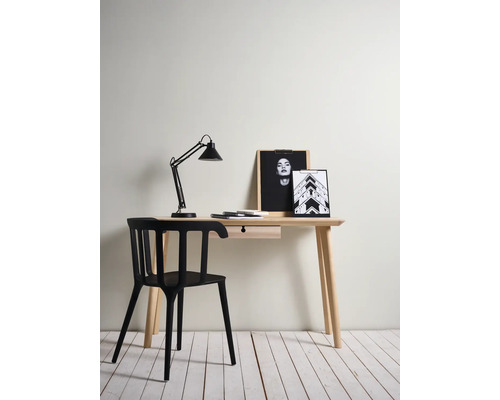 Un bureau avec tiroir, lampe, images et une chaise noire.