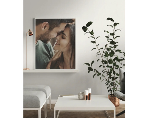 Wohnraum mit gerahmtem Porträt eines Paares, Zimmerpflanze, Couchtisch und Hockern