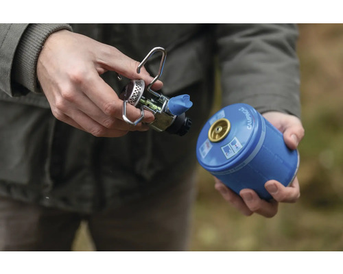 Person, die einen Campingkocher an eine Gaskartusche anschliesst