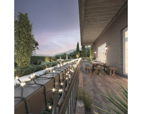 Terrasse mit Lichterkette am Geländer, Tisch und Bänken im Hintergrund.