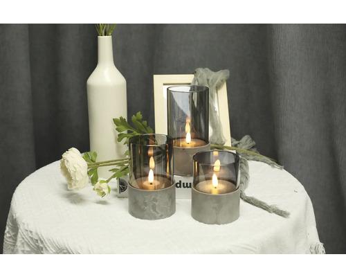 Scène décorative avec trois bougeoirs en verre et béton sur une table