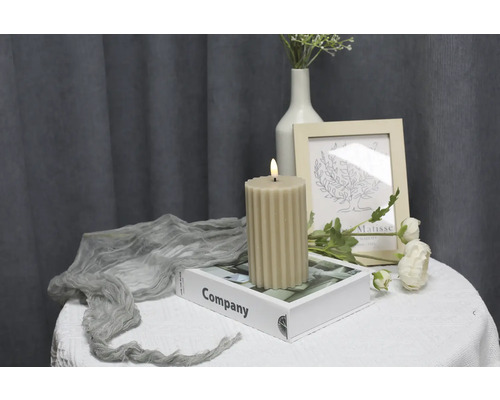 Bougie décorative côtelée sur une table avec livre et décorations