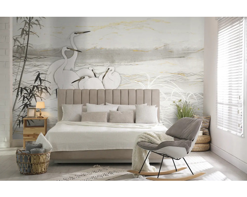 Schlafzimmer mit Bett, Nachttisch, Lampe und dekorativer Wandtapete mit Vogelmotiv