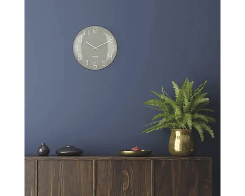 Wohnraum mit Wanduhr, Zimmerpflanze und Holzkommode