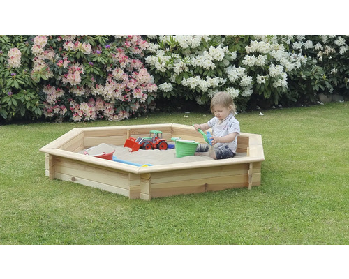 Enfant joue dans un bac à sable en bois dans le jardin