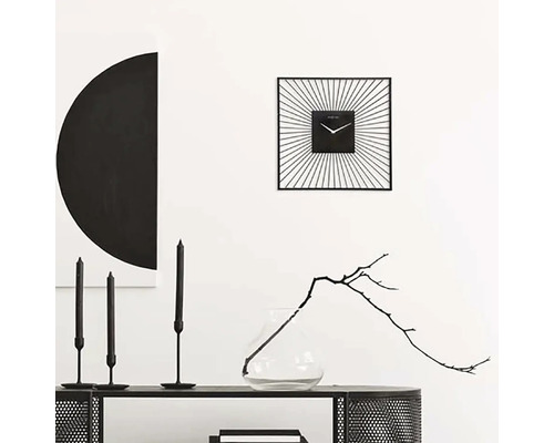Dekoratives Interieur mit einer quadratischen Wanduhr, Kerzen und einer Vase mit Zweig
