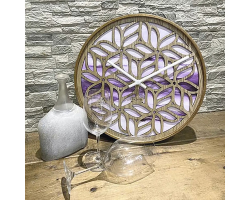 Horloge décorative en bois avec motif de feuilles filigranes à côté de deux verres à vin et d''une bouteille décorative