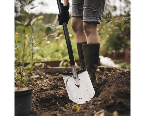 Eine Person gräbt mit einem Spaten im Garten um.