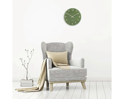 Wohnzimmer mit grüner Wanduhr, Sessel, Kissen und Decke.