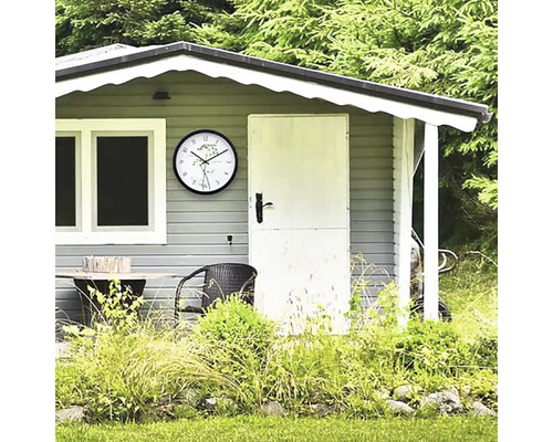 Gartenhaus mit Uhr, Tisch und Stuhl vor Bäumen