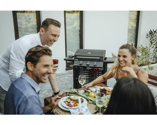 Des personnes sont assises à une table avec un barbecue en arrière-plan