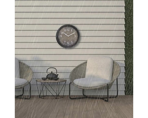 Szene mit einer Wanduhr, zwei Stühlen und einem Tisch im Freien bei Regen.