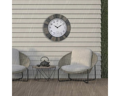 Scène d''extérieur avec une horloge murale résistante aux intempéries au-dessus de deux fauteuils et d''une petite table
