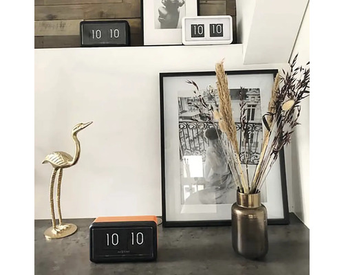 Scène décorative avec réveil à rabat, vase à fleurs, cadre photo et figurine d''oiseau.